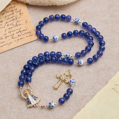 Różaniec z ciemnoniebieskiego popękanego szkła i porcelanowych koralików z Matką Boską z Aparecidy w środku