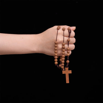 Pleciony różaniec z ciemnego sznurka z imitacji drewna z zawieszką w kształcie krzyża: symbol mało wymagającej ozdoby religijnej