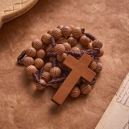 Pleciony różaniec z ciemnego sznurka z imitacji drewna z zawieszką w kształcie krzyża: symbol mało wymagającej ozdoby religijnej