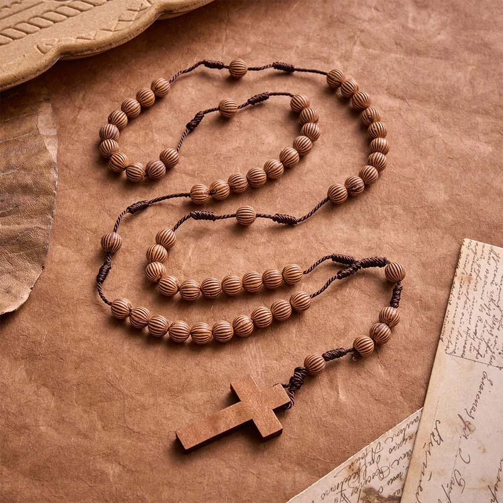 Pleciony różaniec z ciemnego sznurka z imitacji drewna z zawieszką w kształcie krzyża: symbol mało wymagającej ozdoby religijnej