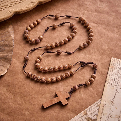 Pleciony różaniec z ciemnego sznurka z imitacji drewna z zawieszką w kształcie krzyża: symbol mało wymagającej ozdoby religijnej