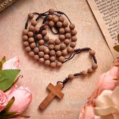 Pleciony różaniec z ciemnego sznurka z imitacji drewna z zawieszką w kształcie krzyża: symbol mało wymagającej ozdoby religijnej