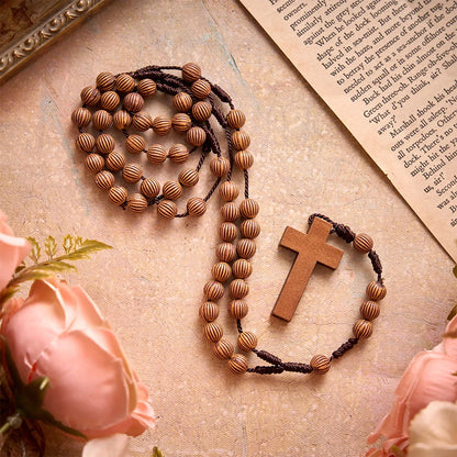 Pleciony różaniec z ciemnego sznurka z imitacji drewna z zawieszką w kształcie krzyża: symbol mało wymagającej ozdoby religijnej